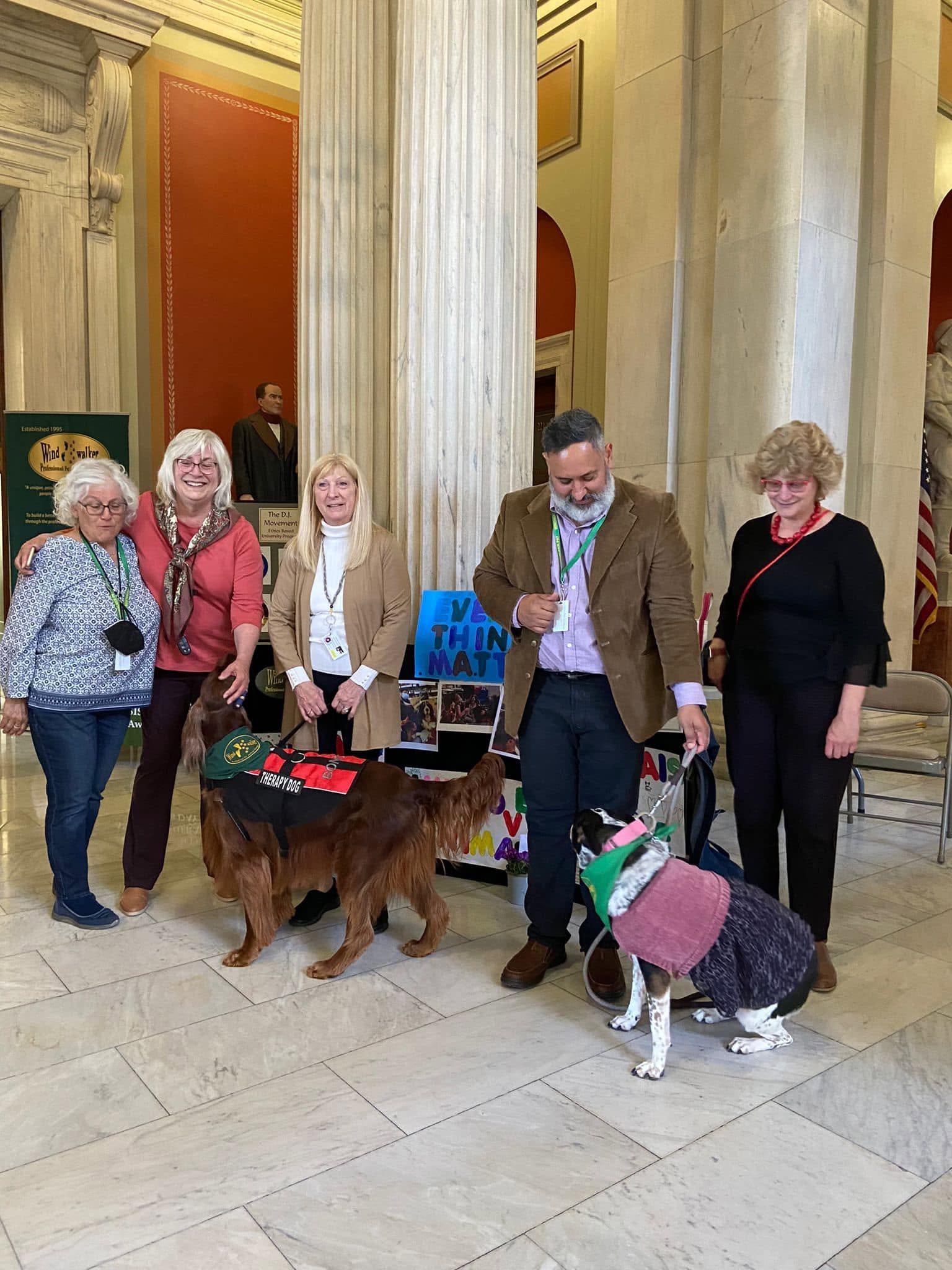 A group of people and trained dogs inside an institutional venue
