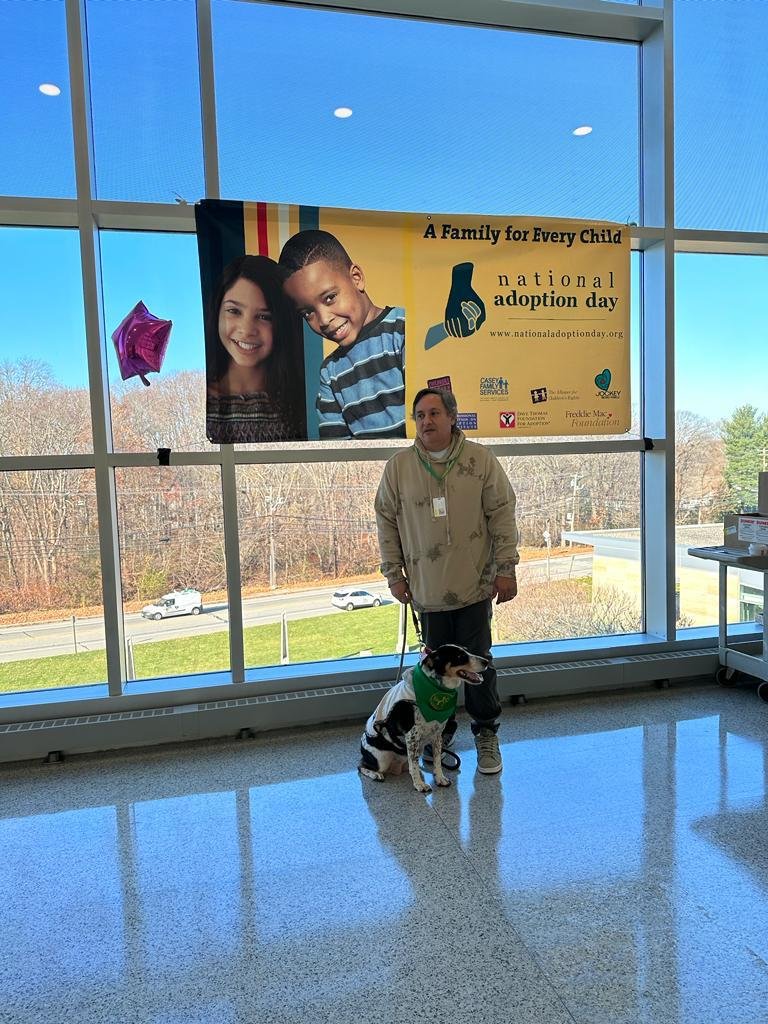 Carlos Moriella, an event participant and Mia beside a National Adoption Day sign