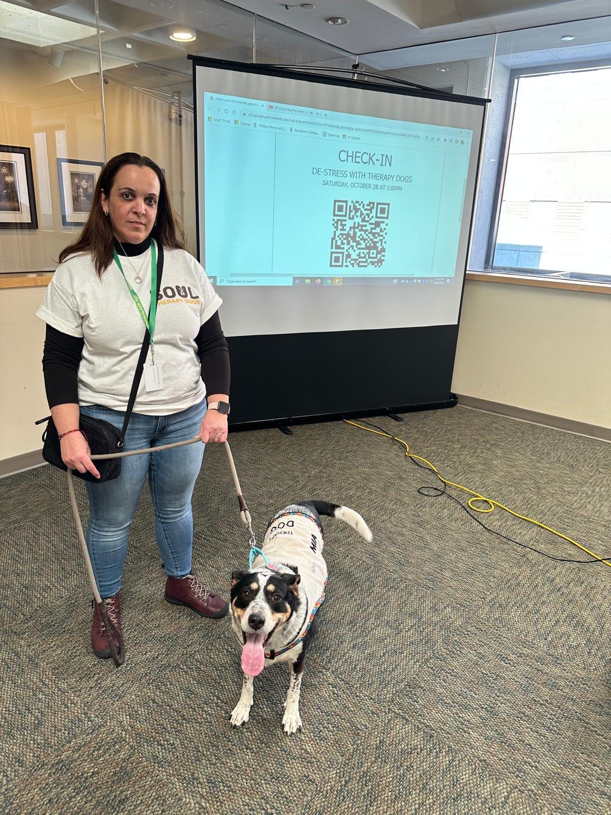 A facilitator and dog beside a presentation screen in an educational setting